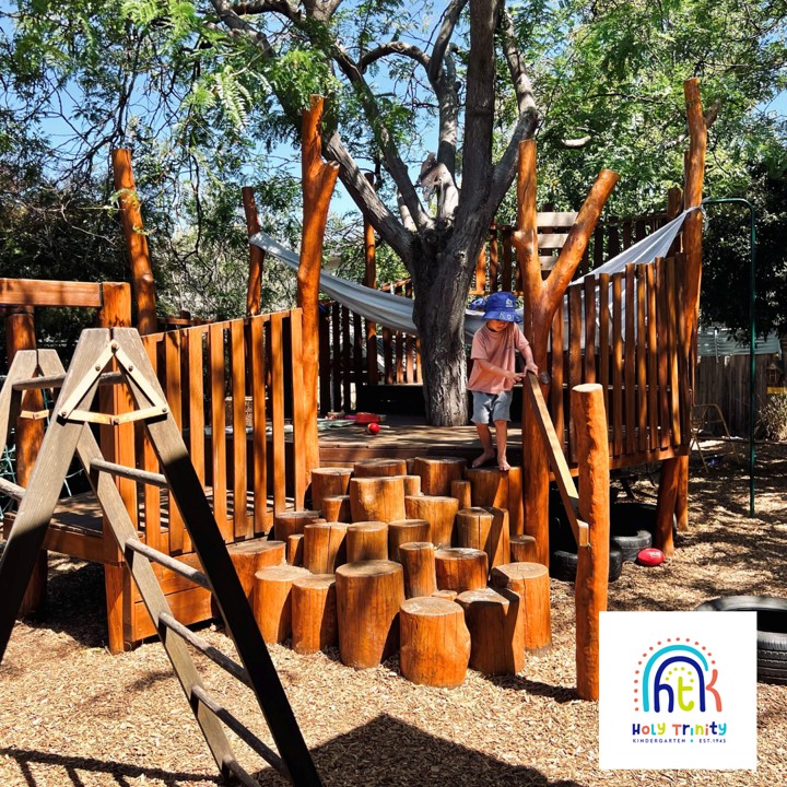 Young child playing on wooden outdoor play equipment