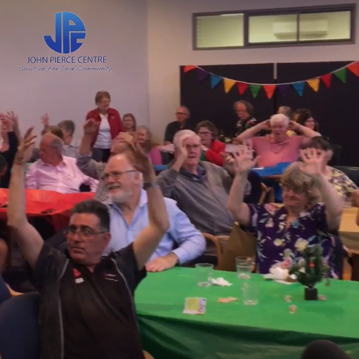 Men and women sitting at tables cheering with their hands up 