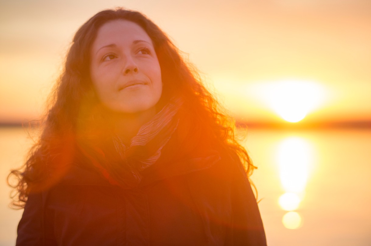 Young woman enjoying a beautiful sunset at the sea.