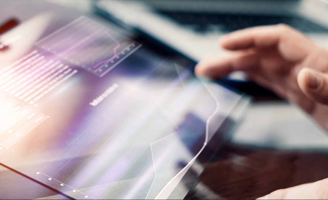 Hand hovering over a tablet displaying graphs. 